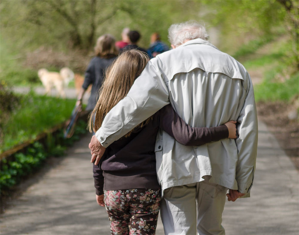 elderly couple holding eachother while strolling park